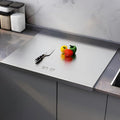 Woman chopping vegetables on stainless steel cutting board in a kitchen in Lahore.